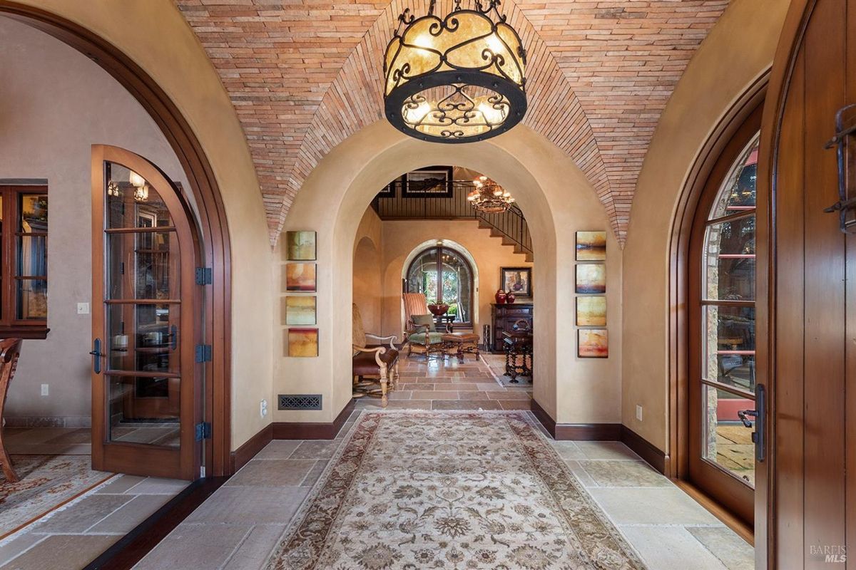 Elegant arches and a warm chandelier highlight the inviting entryway.