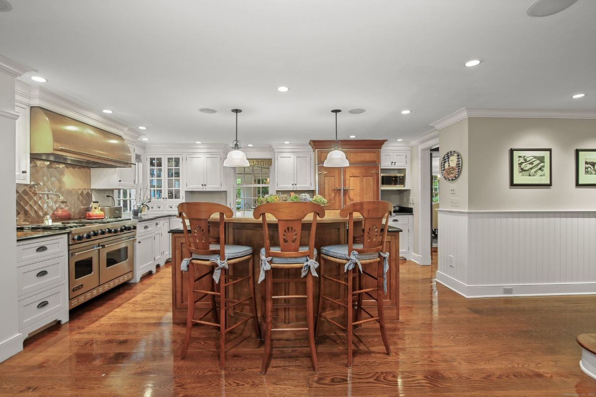 Chef's kitchen featuring a professional-grade range, custom cabinetry, and a large island with bar seating.