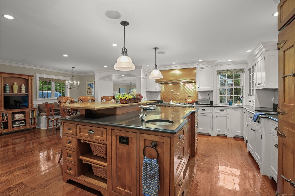 Chef's kitchen featuring a large central island with a prep sink, custom cabinetry, and a golden backsplash complementing the high-end stainless-steel appliances.