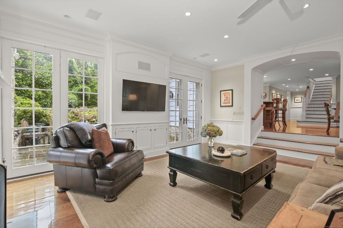 Family room with French doors, a mounted flat-screen TV, and a cozy seating area, seamlessly connected to the dining space and staircase.