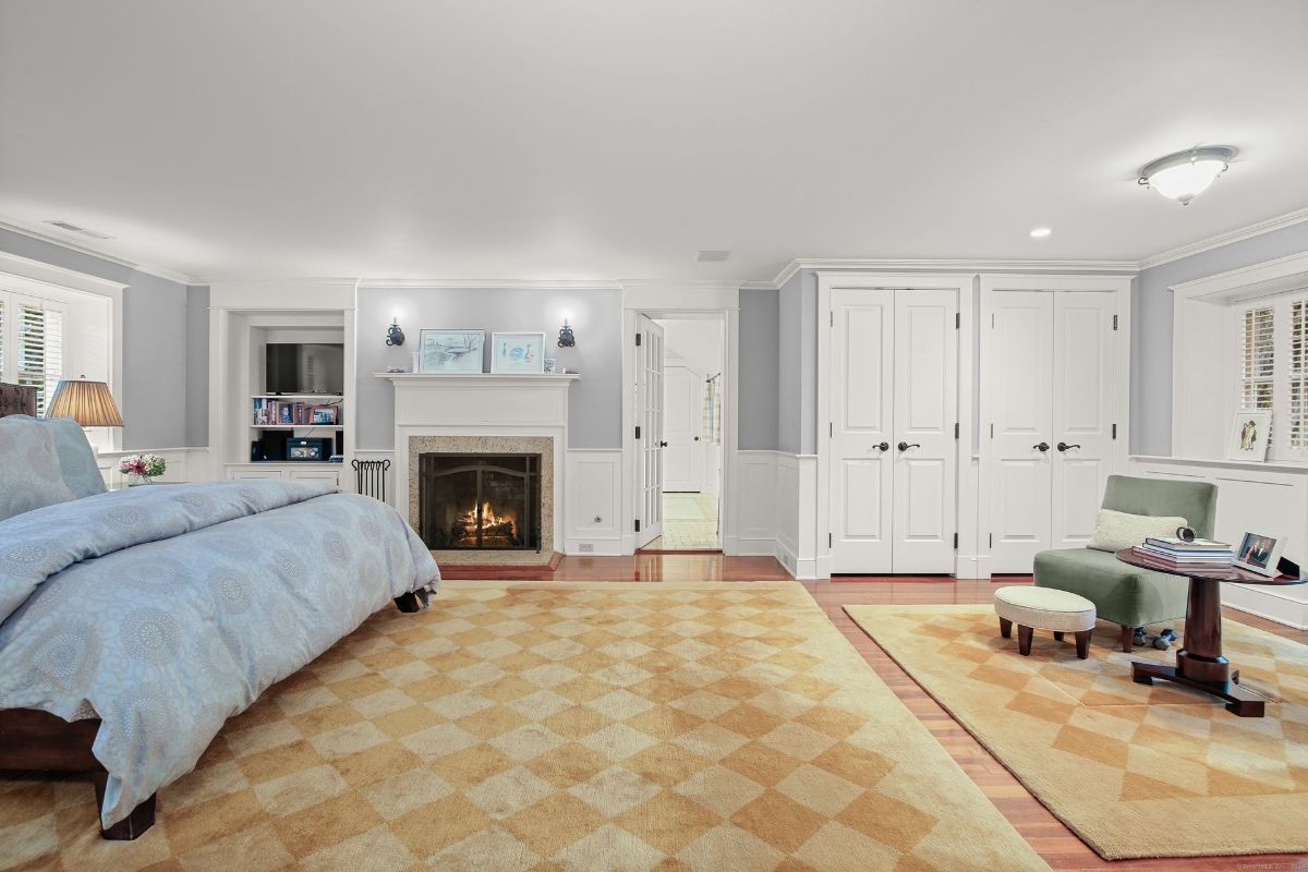 A luxurious bedroom featuring soft lavender walls, a cozy fireplace, custom built-ins, and a reading nook with natural light.