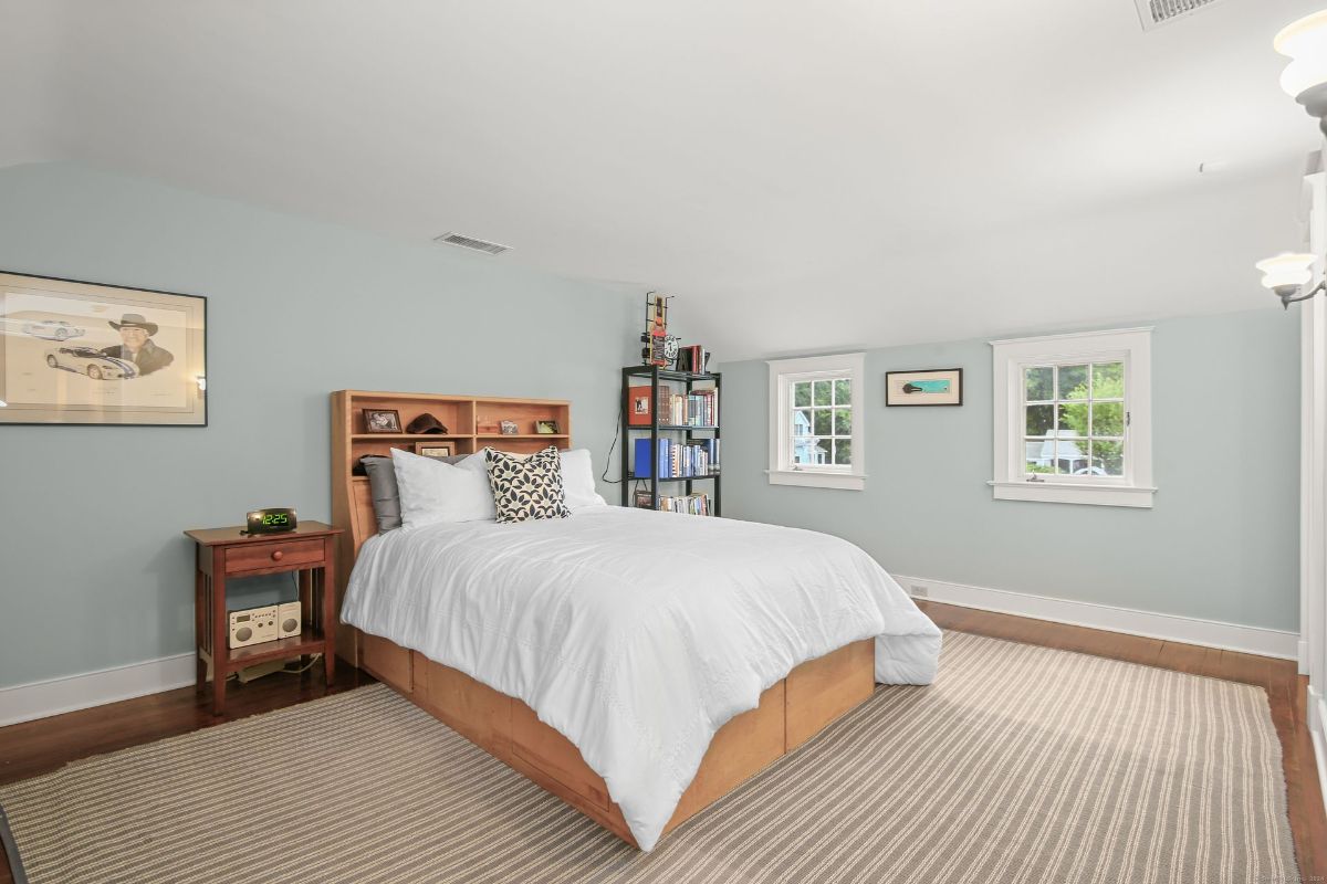 Bedroom featuring soft blue walls, a bed with built-in shelving, and a corner bookshelf adding functionality and charm.