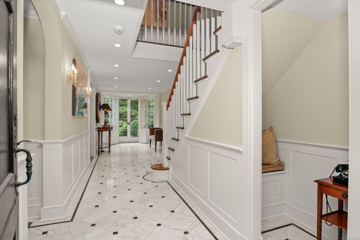 Sophisticated entryway featuring marble flooring, classic wainscoting, and an elegant staircase leading to the upper level.