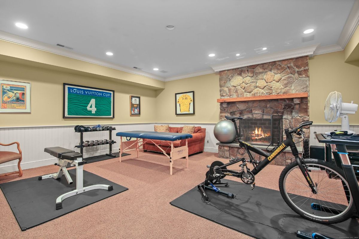 Cozy fitness and relaxation space featuring a stone fireplace, workout equipment, and sports memorabilia.