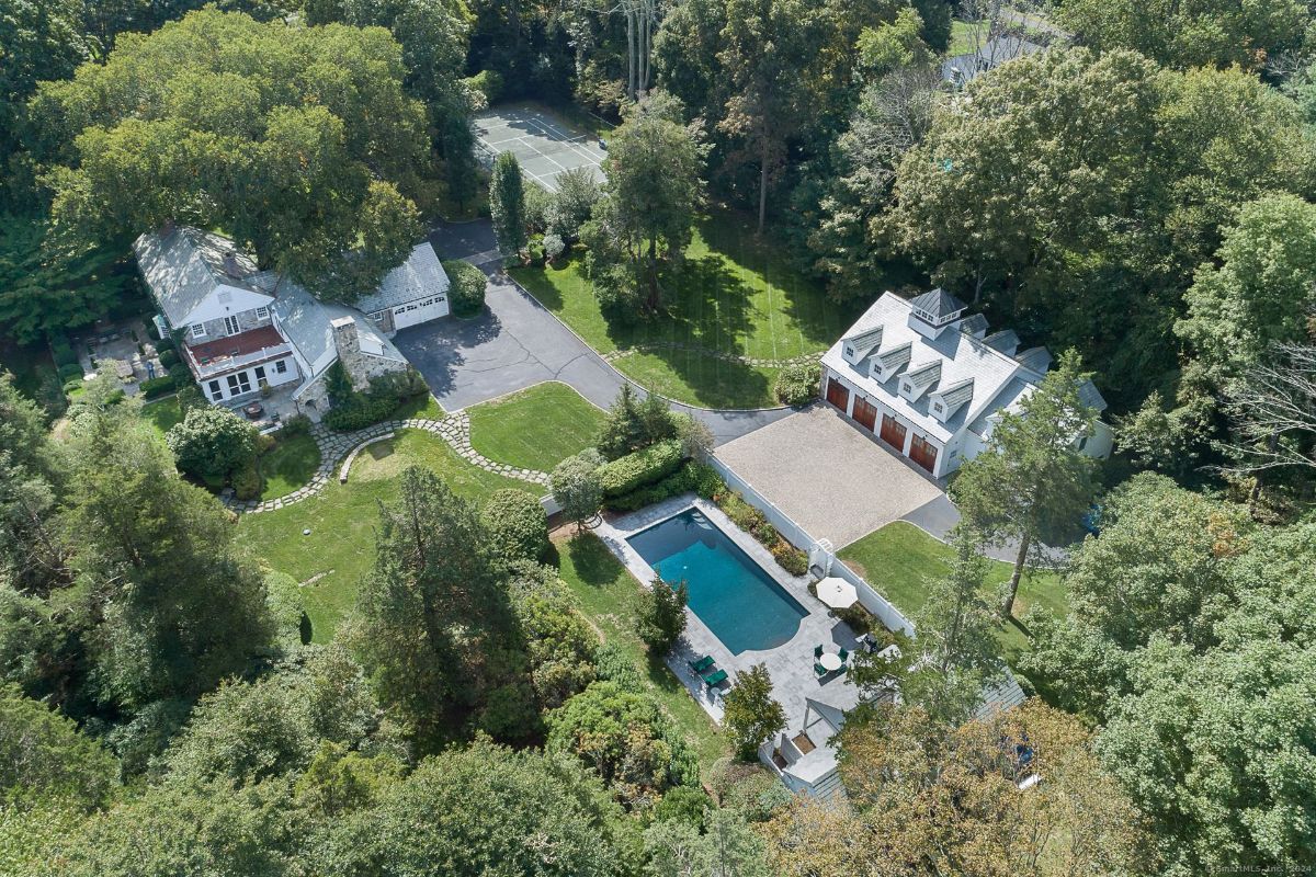 Expansive estate aerial view showcasing a pool, tennis court, detached garage, and lush landscaping.