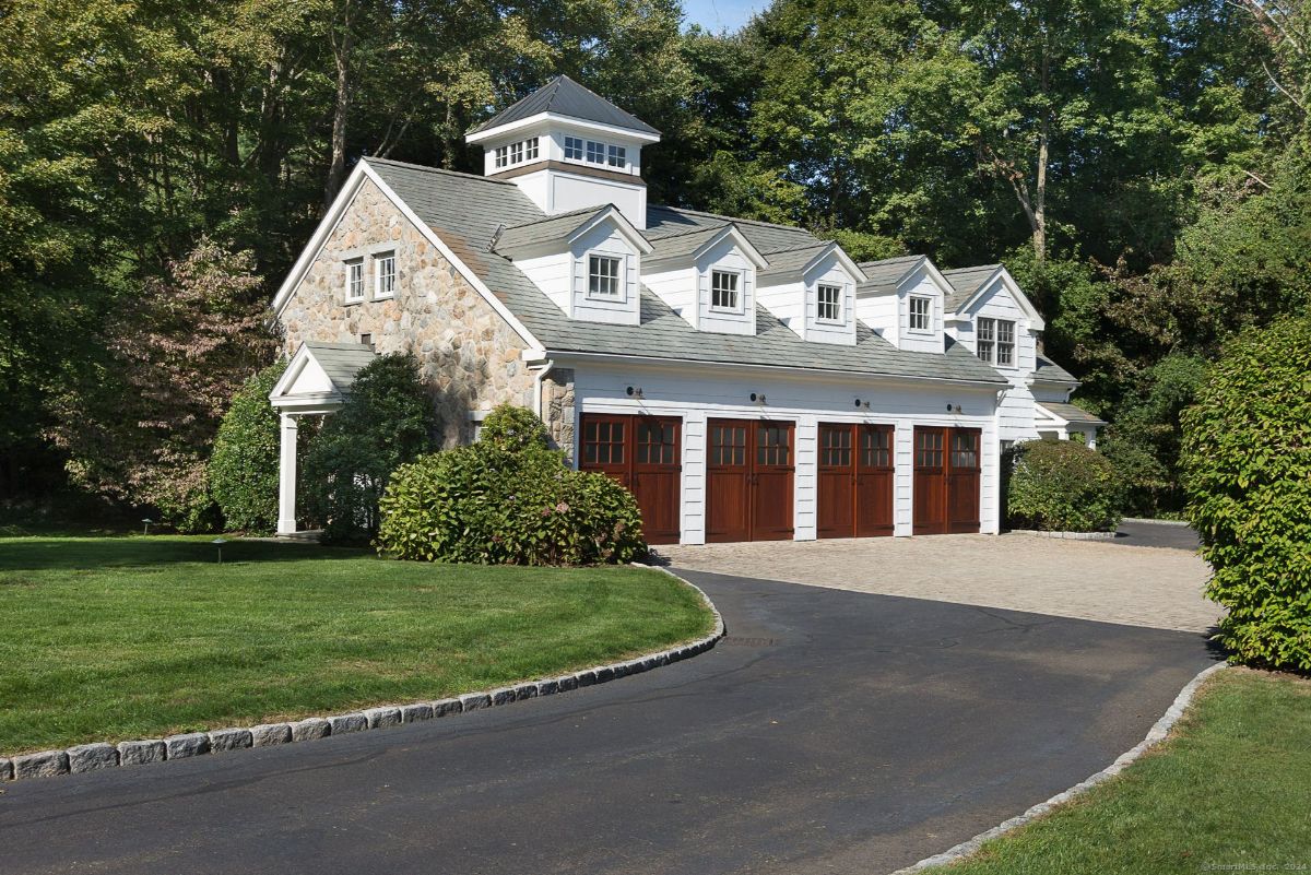 Detached garage with stone accents, dormer windows, and wooden carriage-style doors.