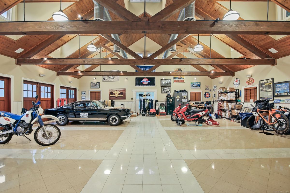 Expansive garage with vaulted wood-beam ceilings, tiled floors, and space for cars and motorcycles.