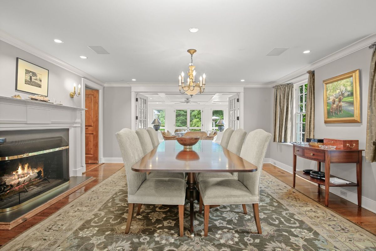 Refined dining area with a polished wooden table, soft upholstered chairs, and a glowing fireplace accenting the elegant ambiance.