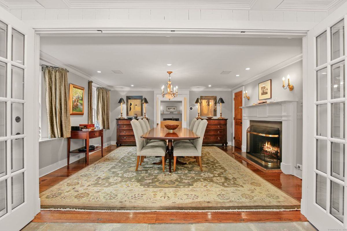 Elegant formal dining room featuring a chandelier, cozy fireplace, and rich wooden furnishings.