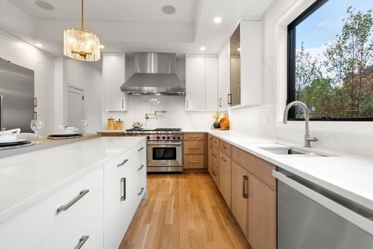 Kitchen layout featuring a large island, stainless steel appliances, custom cabinets, and a contemporary light fixture.