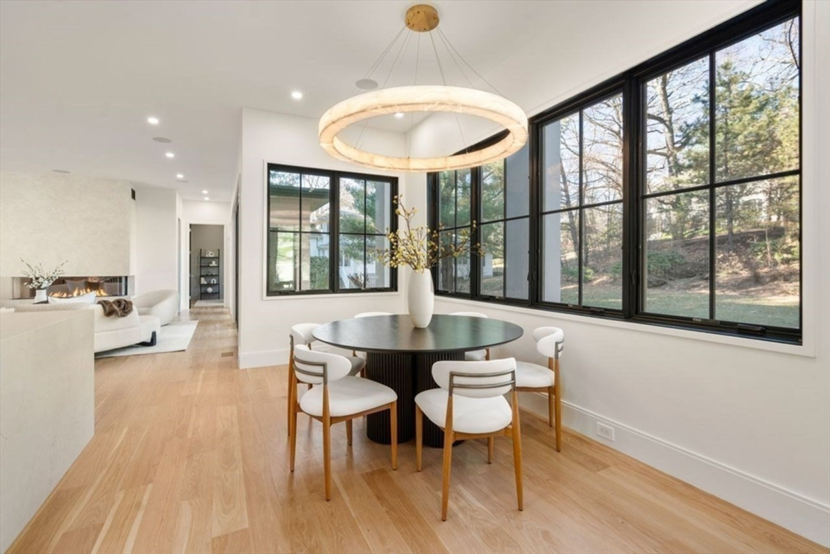 Bright dining nook framed by large windows and a chic circular chandelier.