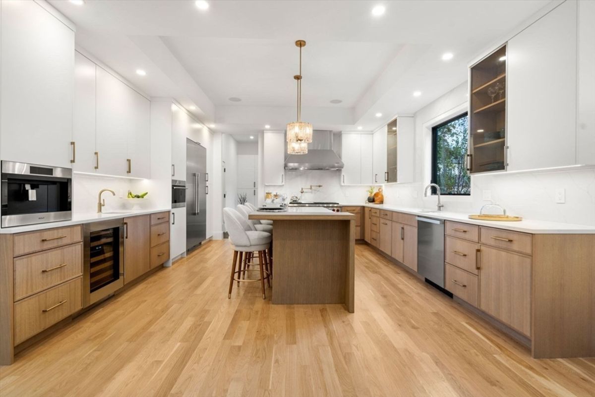 Kitchen layout featuring warm wooden cabinetry, sleek countertops, and a central island with seating.