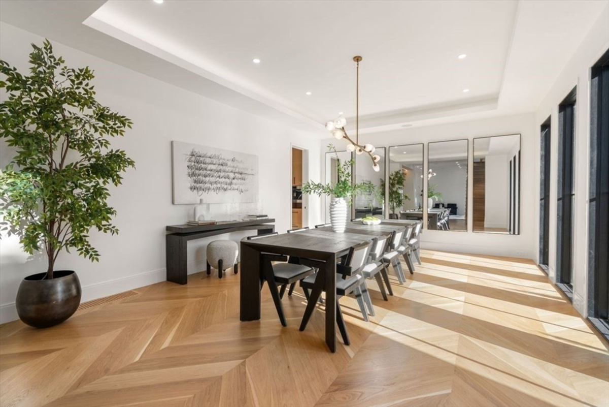 Expansive formal dining room with elegant wood flooring and contemporary lighting.