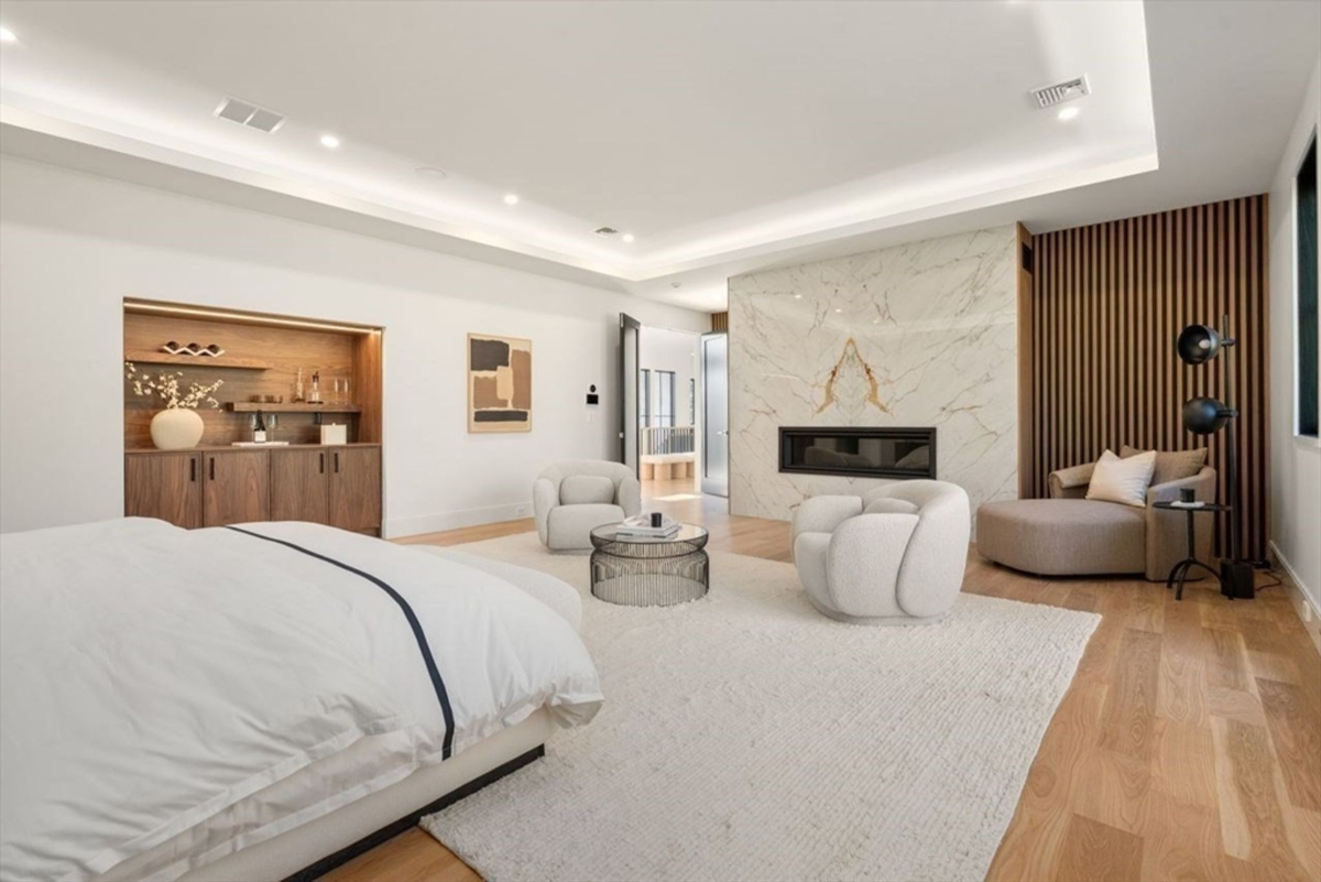 Master bedroom includes a stylish fireplace wall with marble and wood elements.