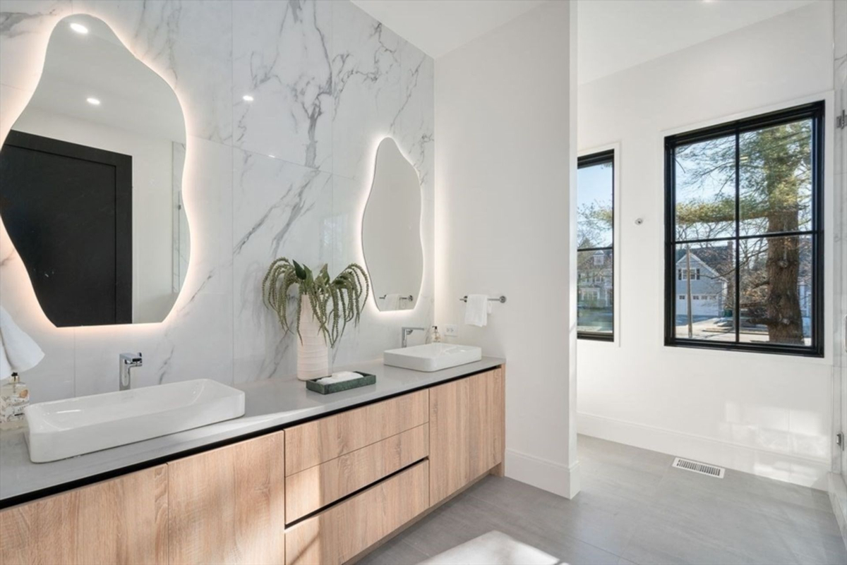 Elegant double vanity setup with custom wood cabinetry and illuminated mirrors.