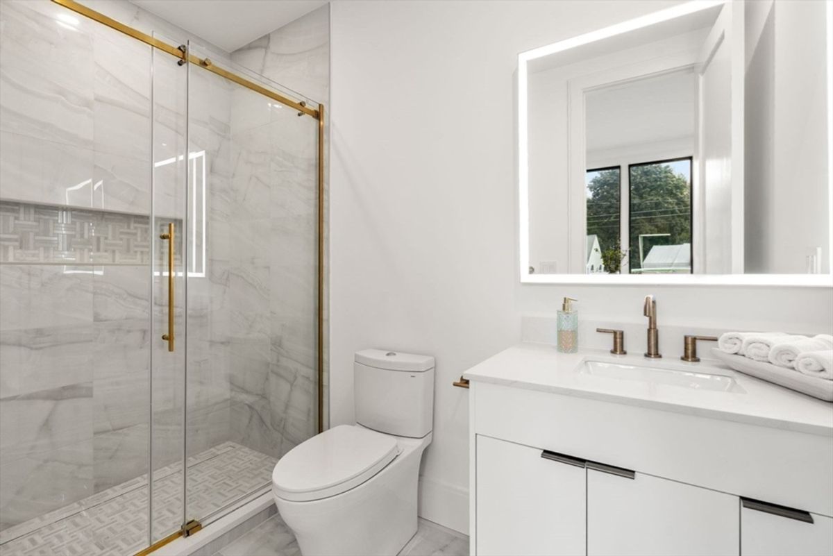 Elegant bathroom with a marble-inspired walk-in shower and modern brass fixtures.