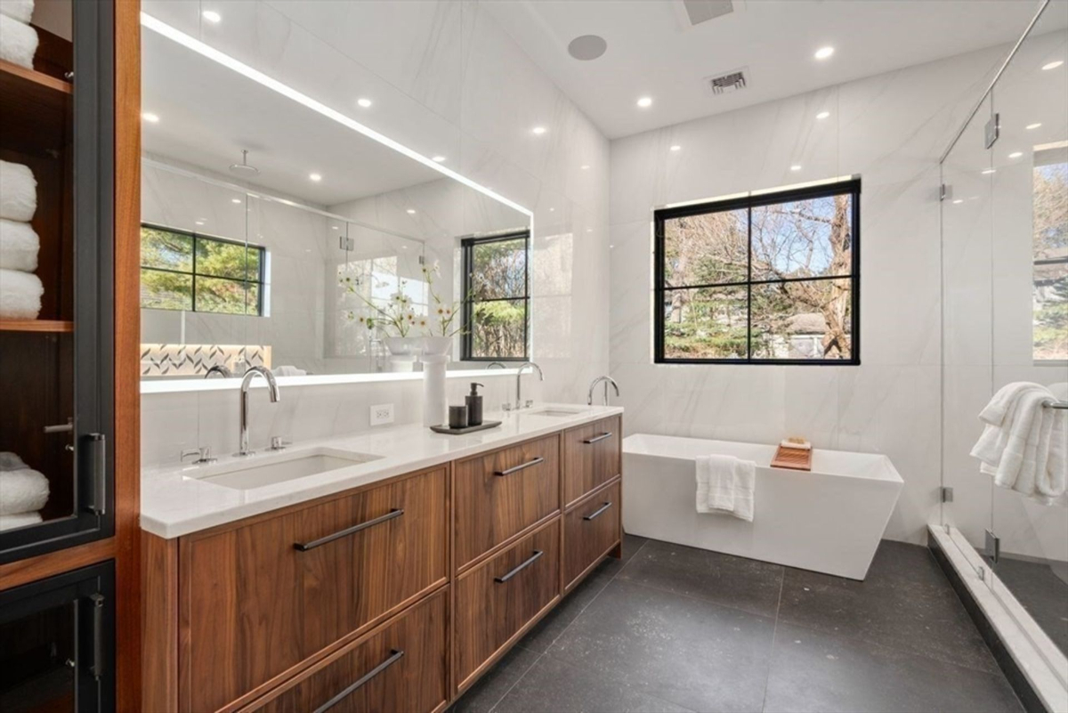 Elegant bathroom featuring a double vanity with walnut cabinetry and a freestanding soaking tub.