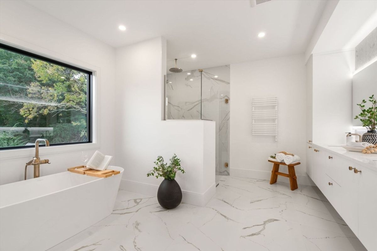 Luxurious bathroom featuring a freestanding soaking tub, marble flooring, and a spacious glass-enclosed shower.