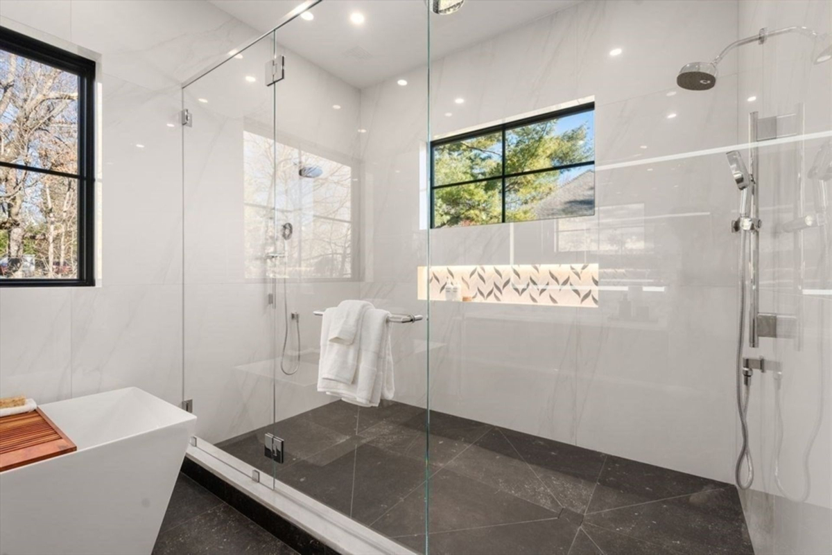 Spacious glass-enclosed shower with modern fixtures and a large window bringing in natural light.