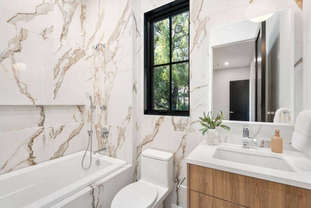 Secondary bathroom with luxurious marble walls and a contemporary vanity.