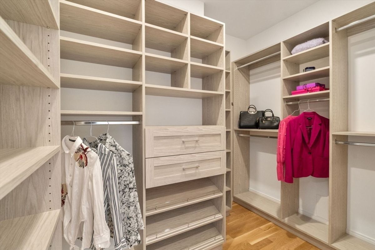 Walk-in closet featuring custom shelving, hanging rods, and integrated drawers with a light wood finish.