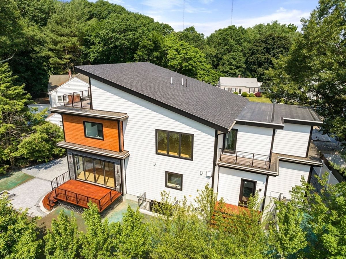 Aerial view showcases a contemporary home surrounded by lush greenery.