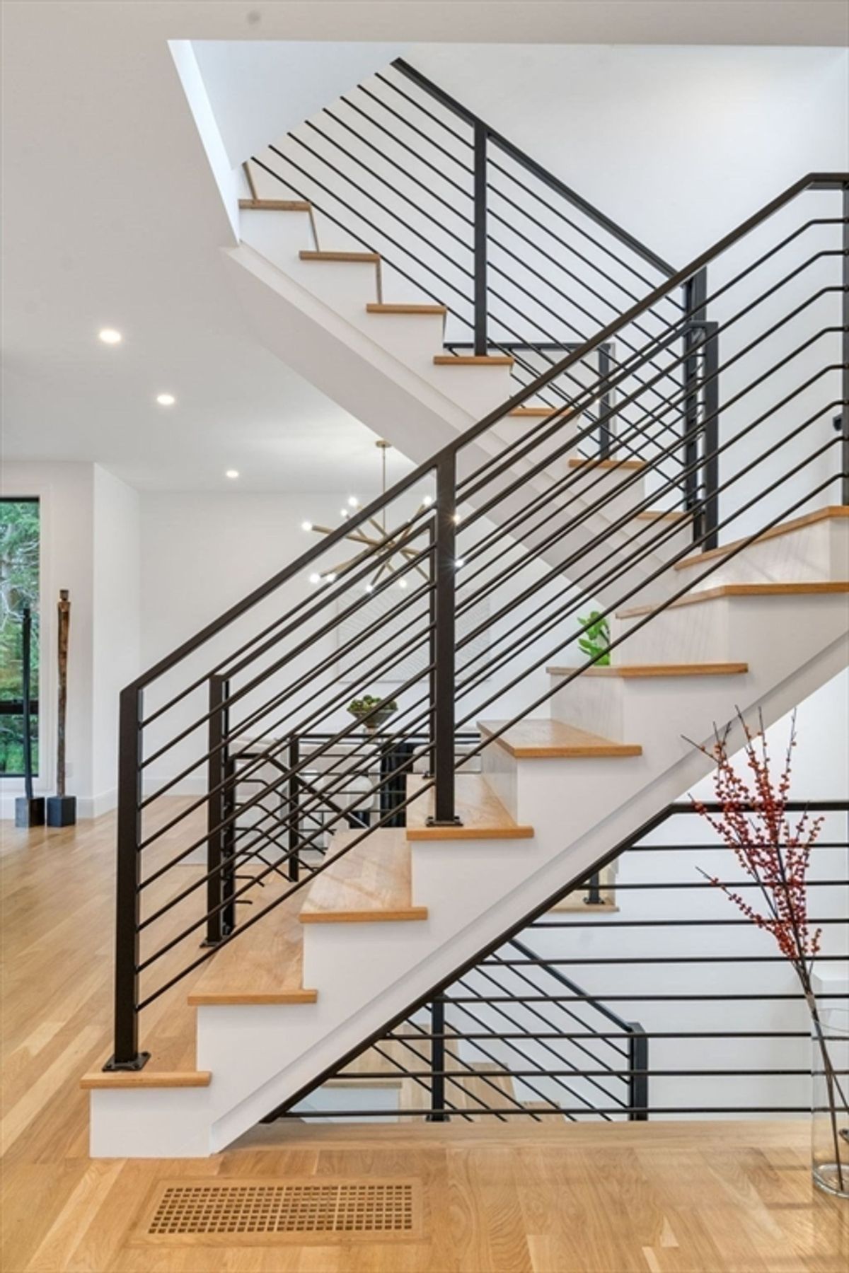 Elegant staircase featuring modern black railings and natural wood steps in an open-concept layout.