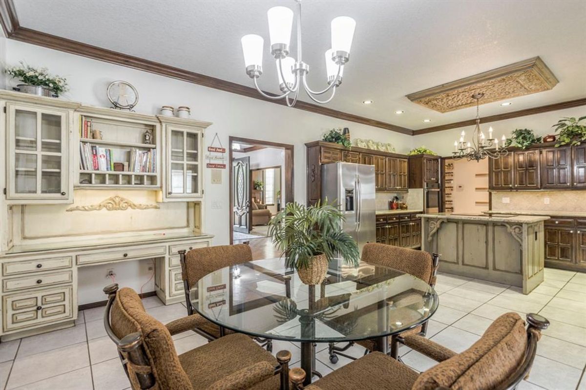 Cozy breakfast nook features a glass-top dining table and an elegant chandelier.