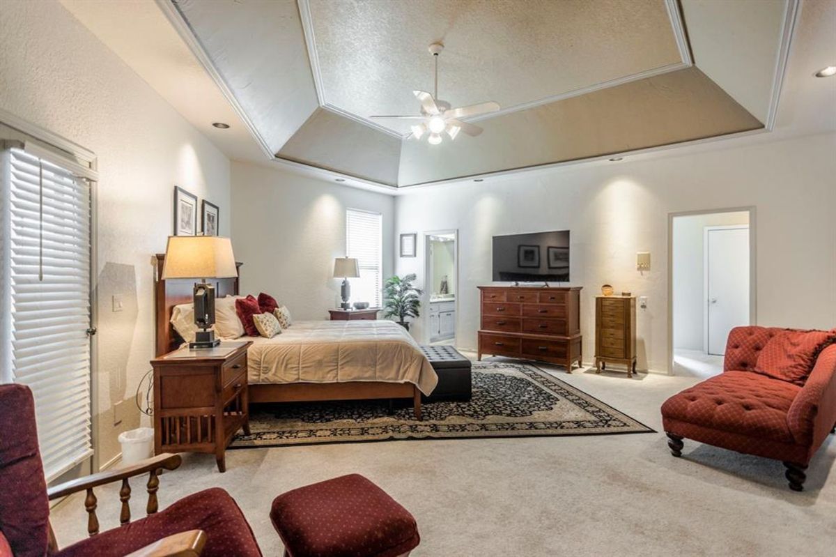 Bedroom with a vaulted ceiling, cozy sitting area, and natural light streaming through the windows.