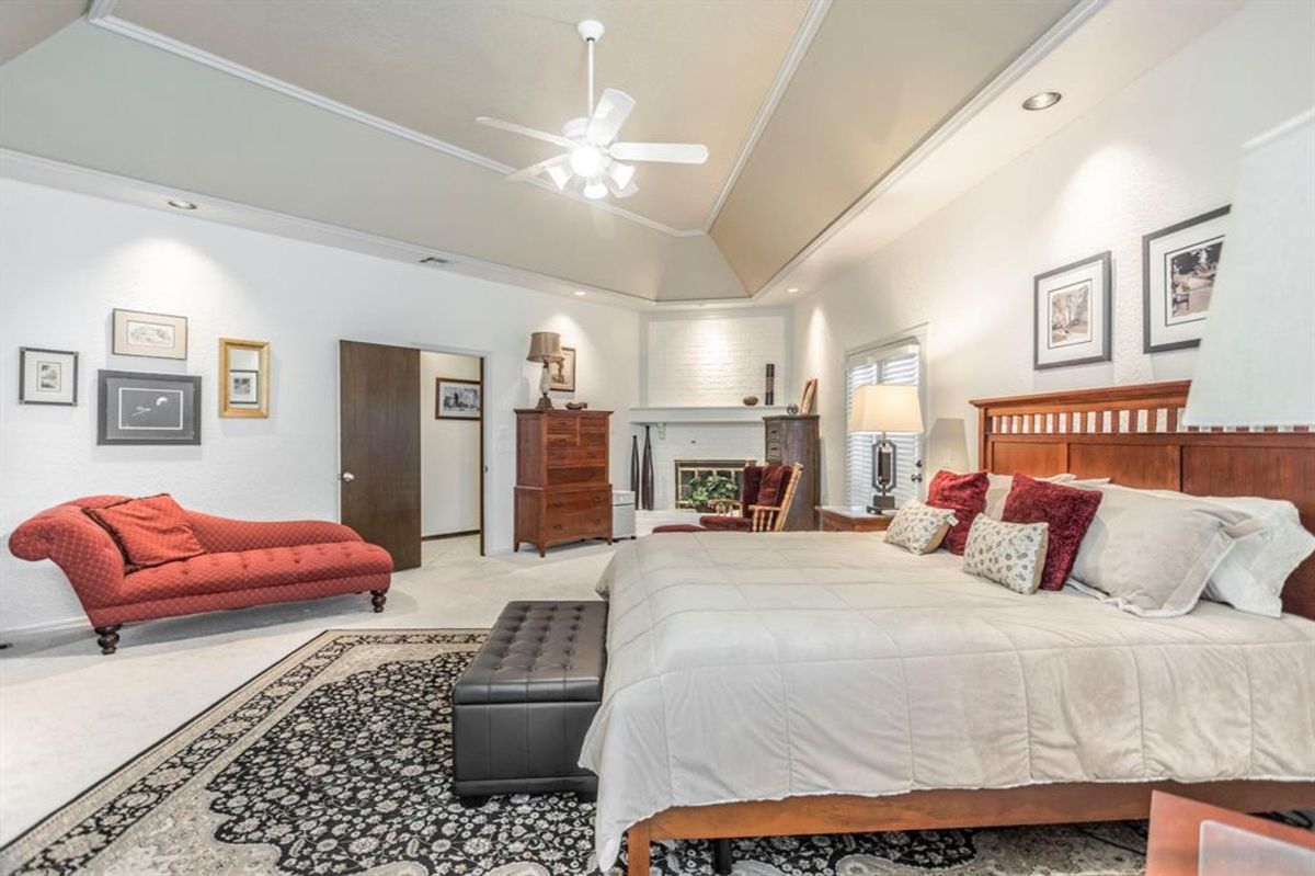 Elegant bedroom with a chaise lounge, fireplace, and recessed lighting creating a warm ambiance.