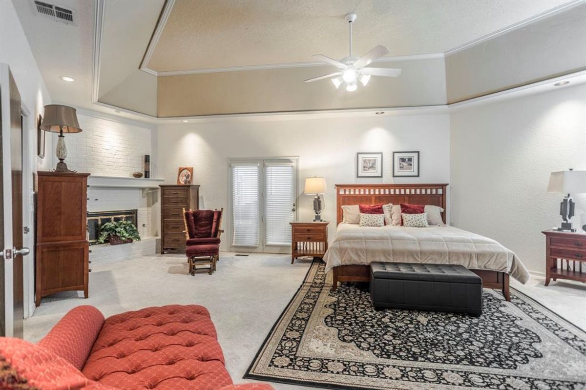 Spacious bedroom with a cozy fireplace, private patio doors, and elegant furnishings.