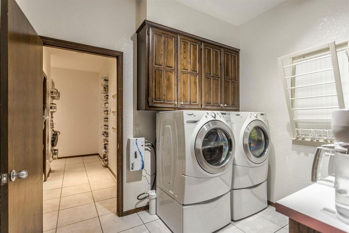 Spacious laundry room with built-in cabinets and adjacent storage pantry.