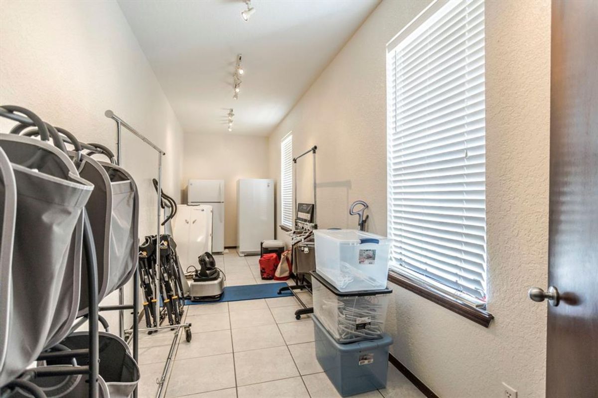 Extended utility room featuring ample storage space, tiled flooring, and large windows for natural light.