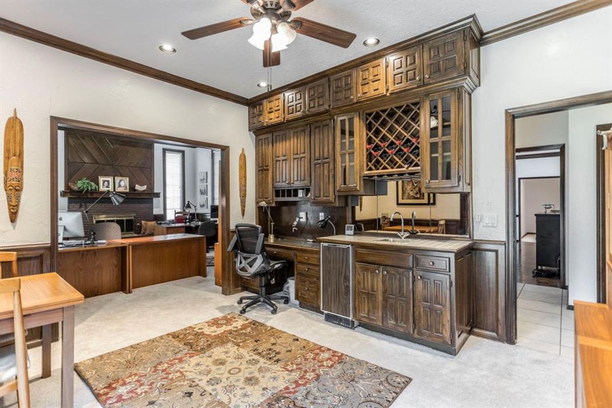 Elegant home office with built-in cabinetry, wine storage, and an adjacent workspace featuring rich wood accents.