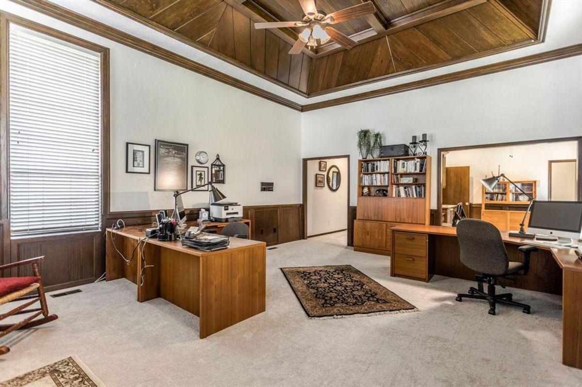 Expansive office space featuring high ceilings with rich wood paneling, multiple workstations, and built-in shelving for a sophisticated and organized workspace.