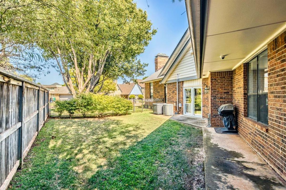 A private backyard with lush greenery, a shaded patio, and a wooden fence offering a serene outdoor retreat.