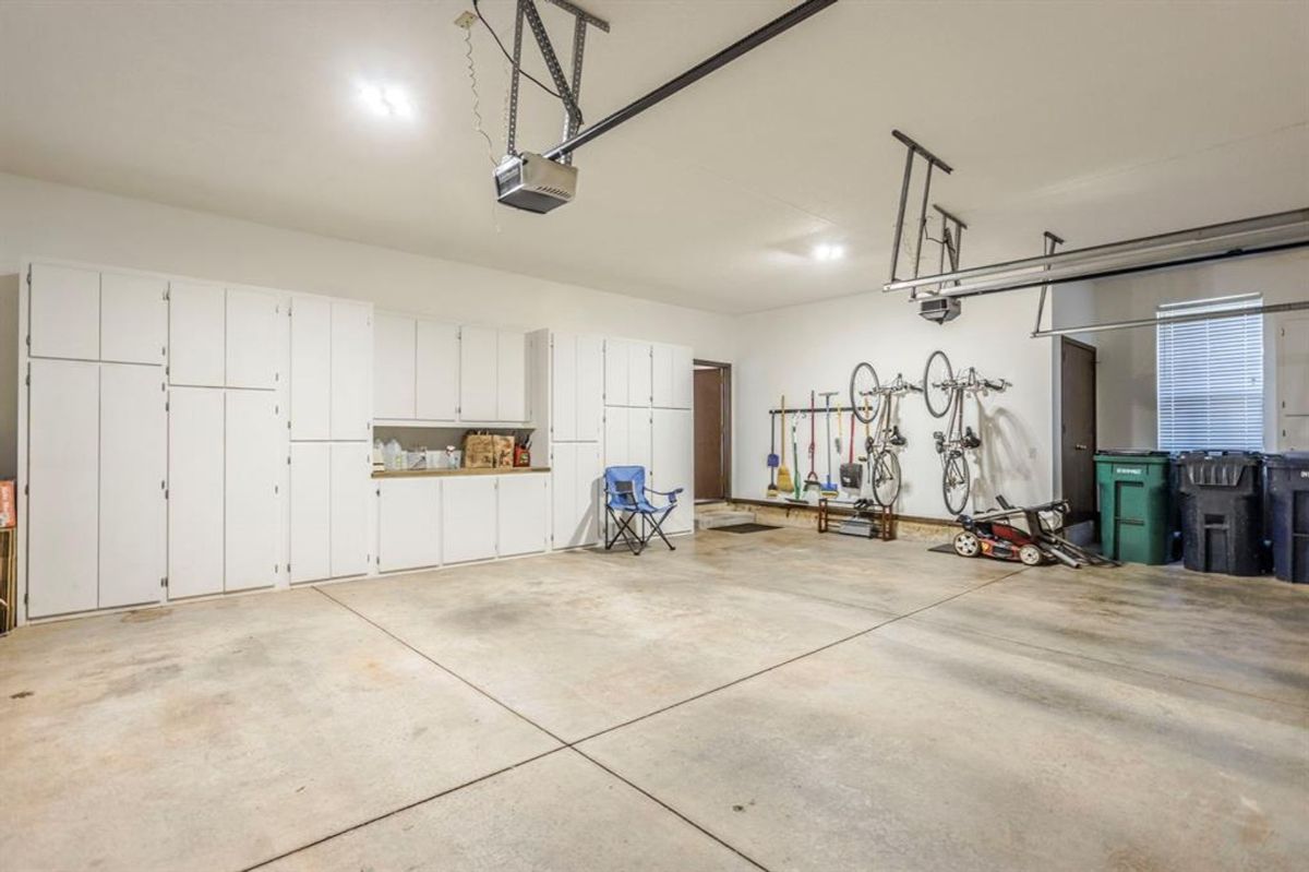 Garage equipped with extensive built-in cabinetry, wall-mounted storage for bikes and tools, and polished concrete flooring for a clean, organized look.