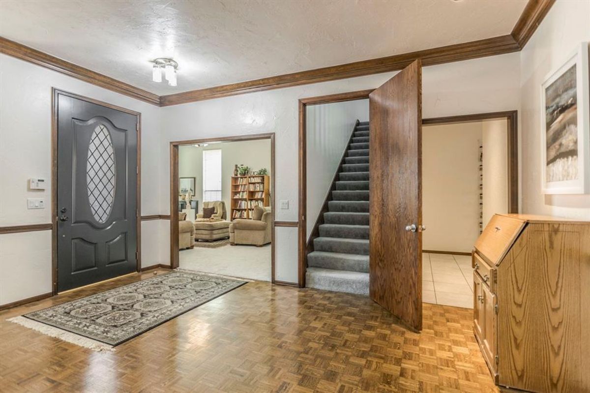 Entryway with parquet flooring, a staircase, and open views to the living and dining areas.