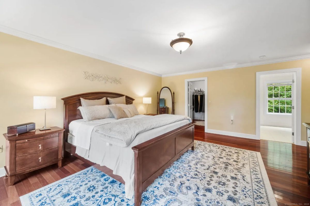 Master bedroom with hardwood floors, beige walls, and a king-size bed.