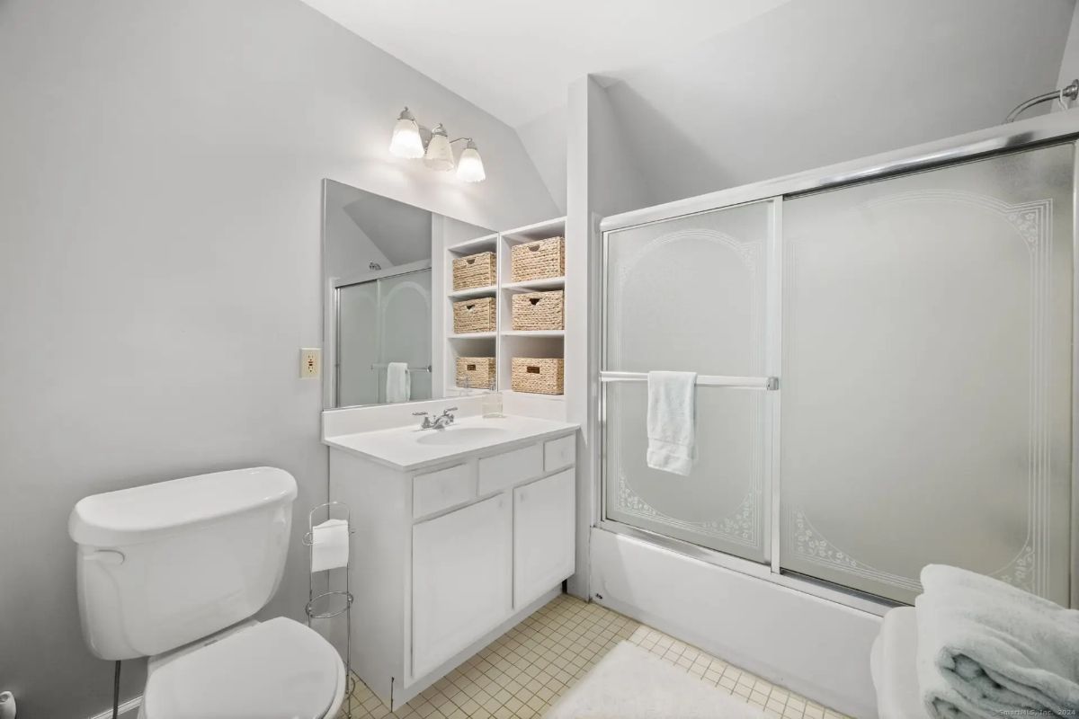 A clean and simple bathroom with gray walls, white fixtures, and a shower/tub combination.