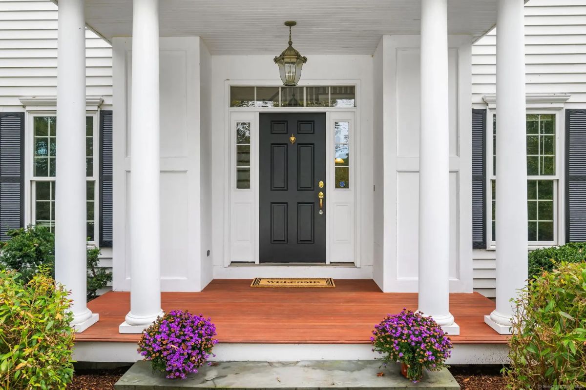 Inviting front entrance framed by classic white columns and decorative potted flowers.