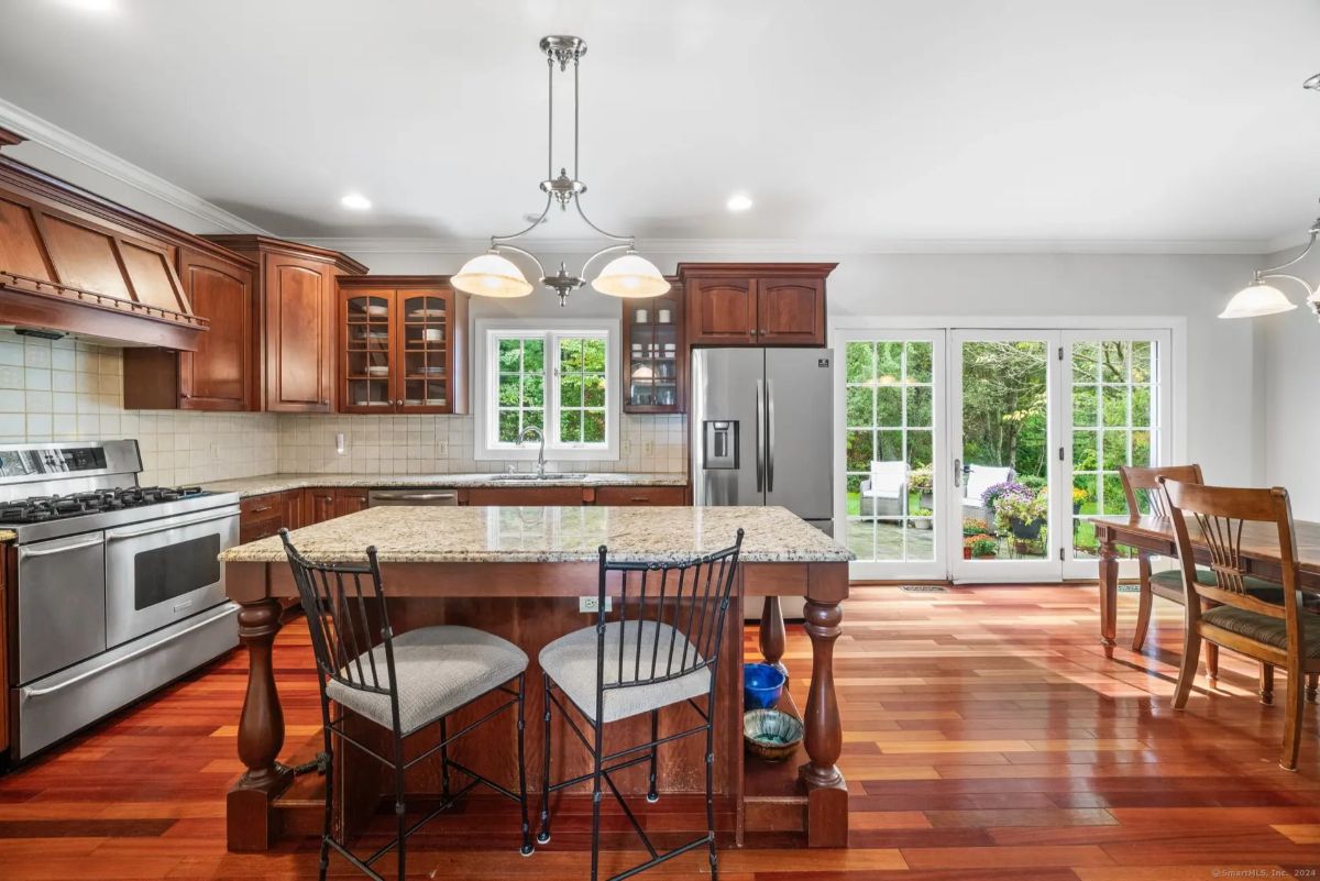 Spacious kitchen featuring rich wood cabinetry, stainless steel appliances, and a granite island with seating.