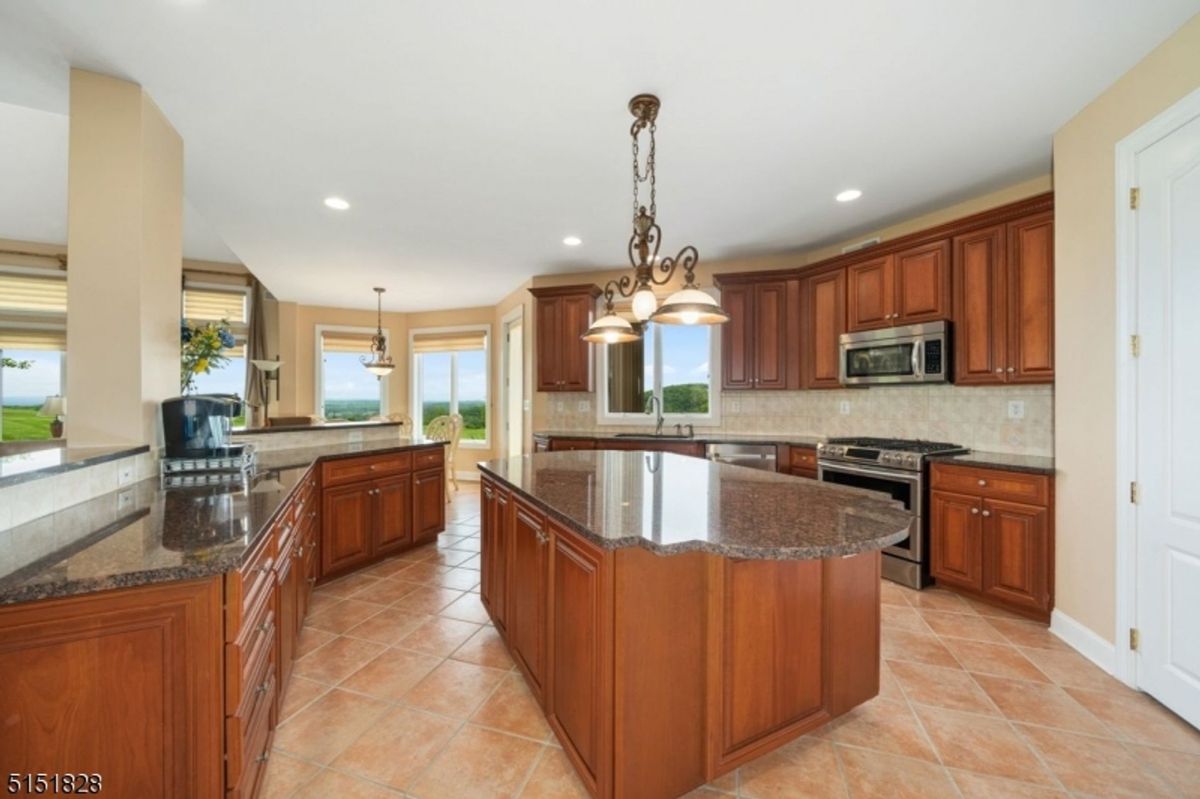 Gourmet kitchen fitted with granite countertops, rich wooden cabinetry, and pendant lighting.