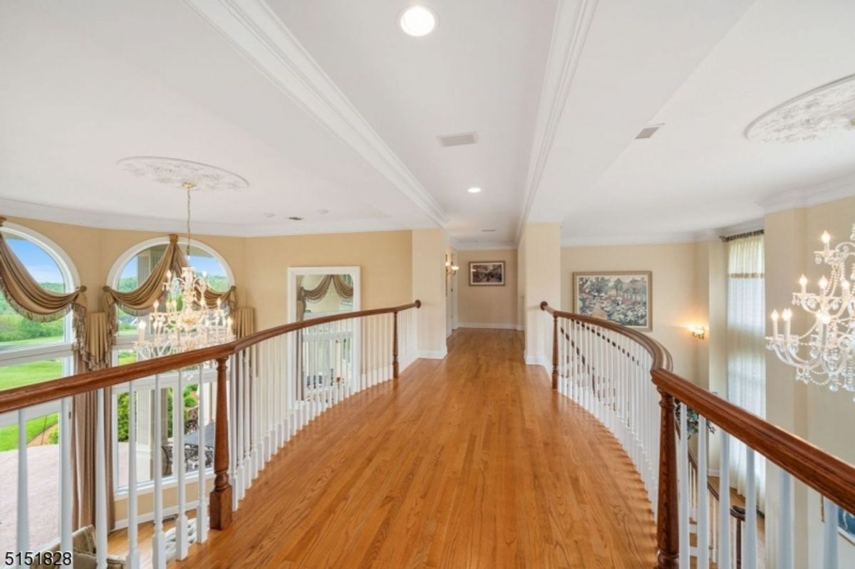 Upper-level hallway with hardwood flooring and an open railing overlooking the living area.