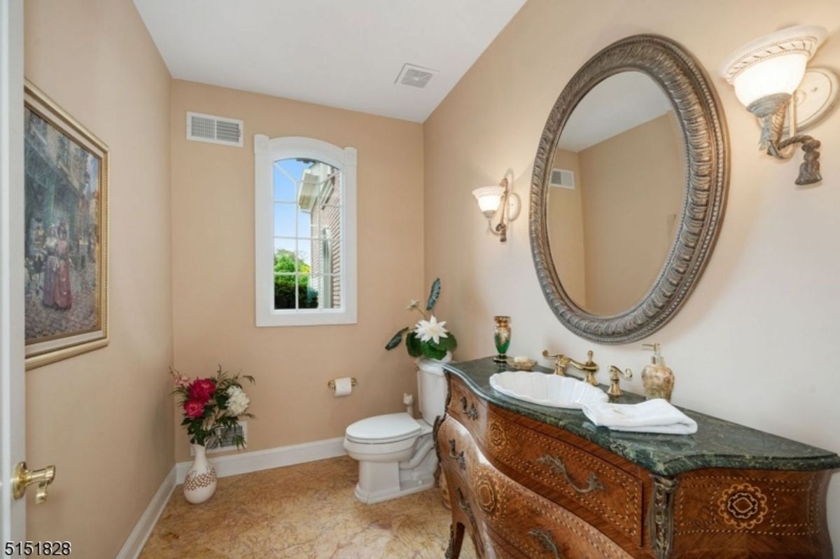 Powder room with ornate vanity and marble countertop.