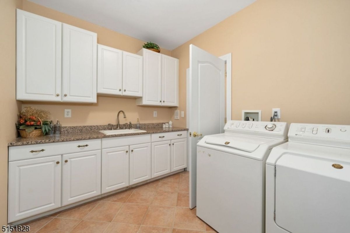 Well-equipped laundry room with ample storage and granite counters.