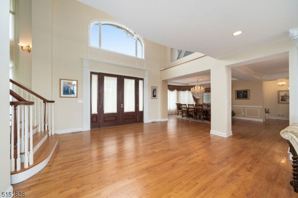 Spacious foyer featuring high ceilings, hardwood floors, and a grand staircase.