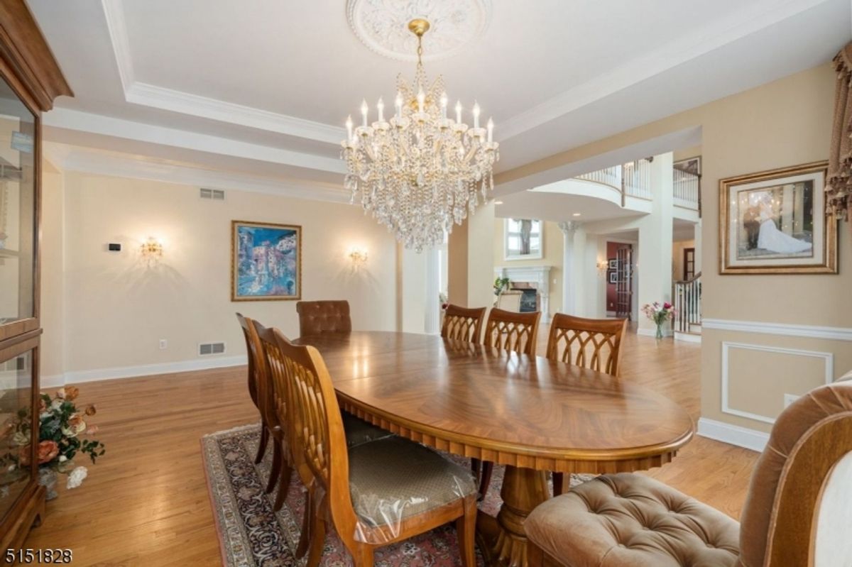 Elegant dining room featuring a crystal chandelier, wooden flooring, and a long dining table.