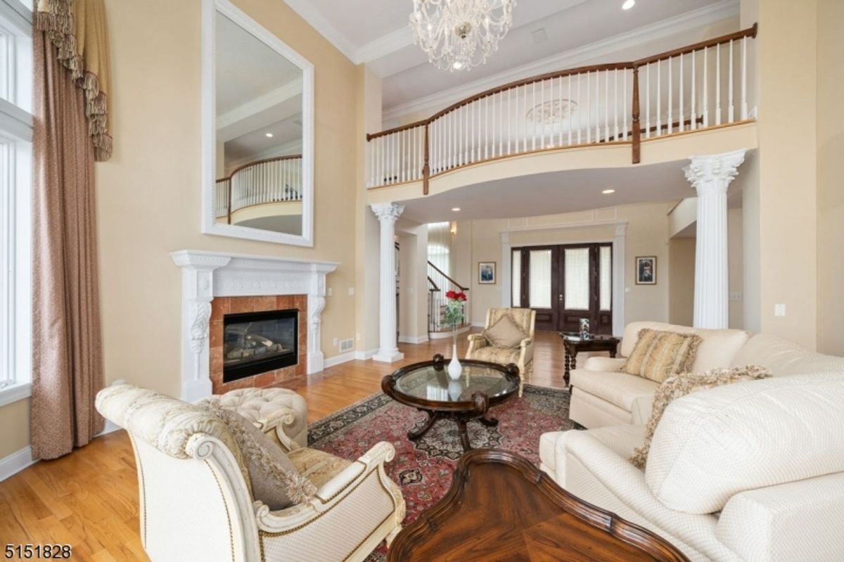 Formal living room with a double-height ceiling and a decorative balcony overlook.