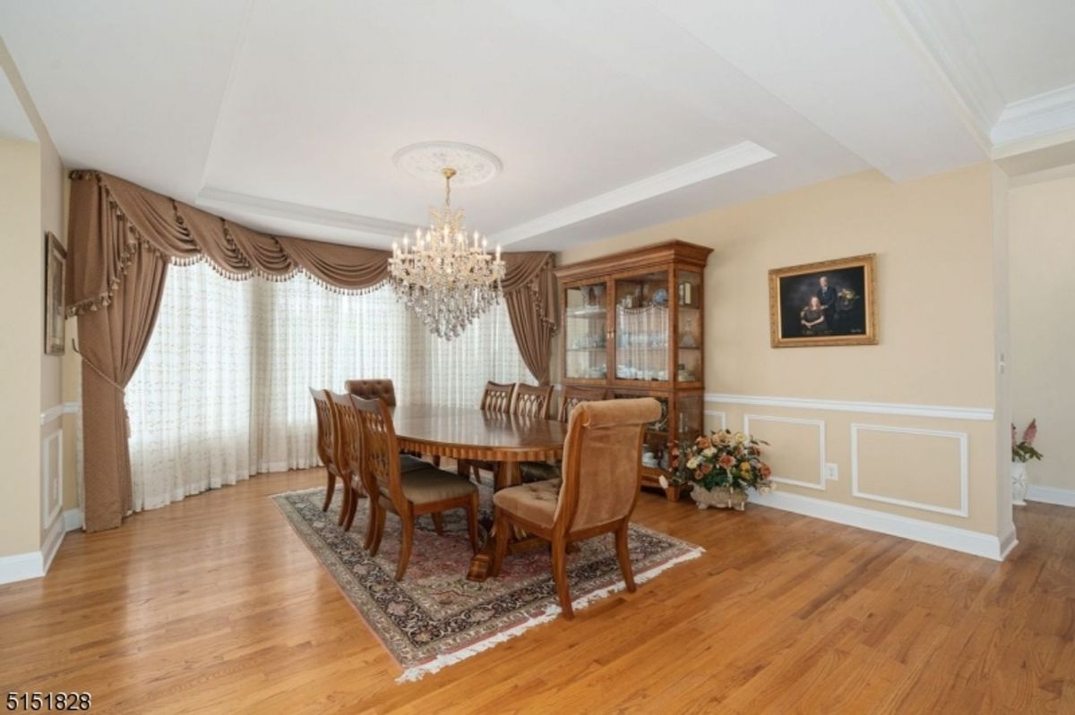 Spacious formal dining room with natural light and ornate curtains framing the windows.